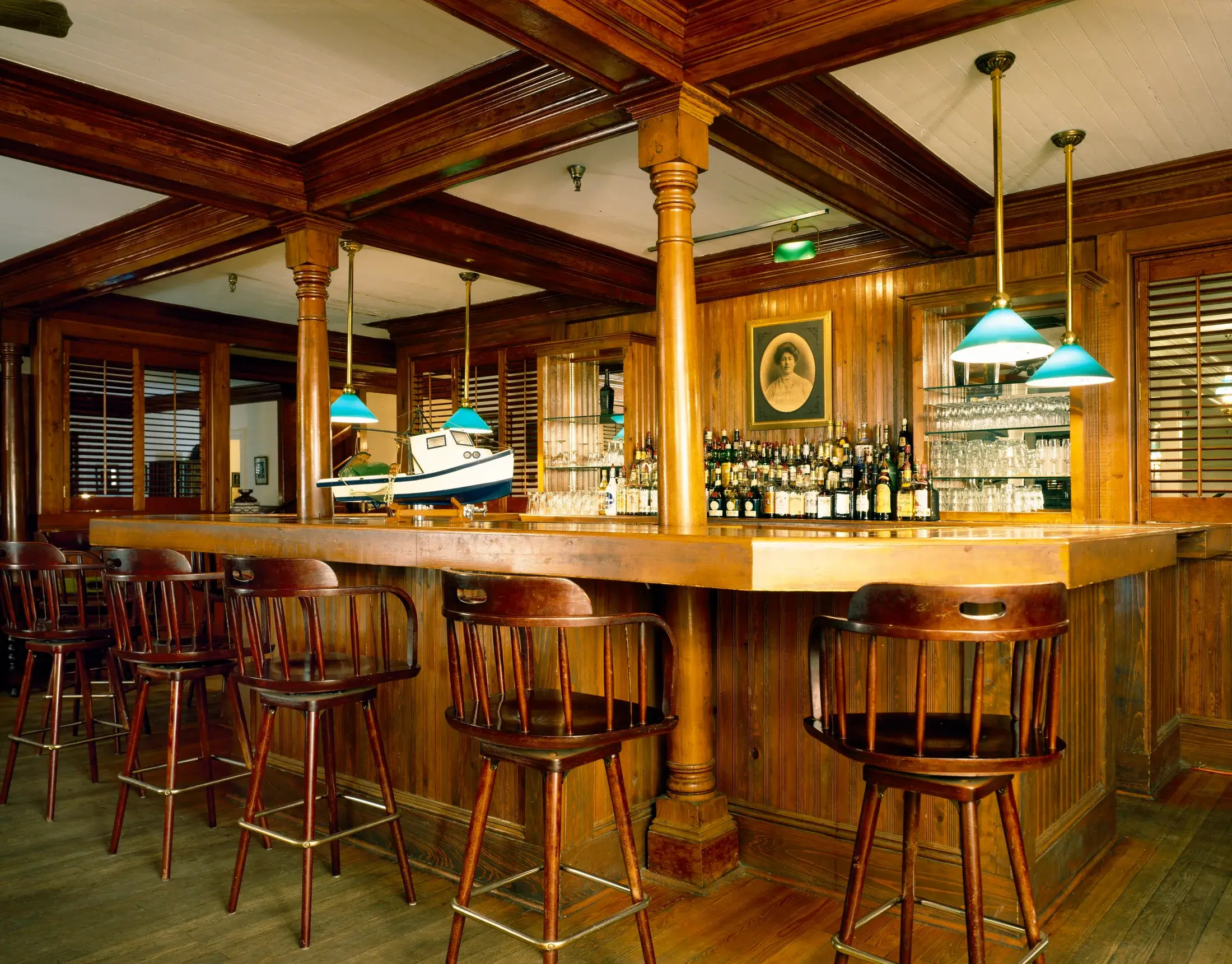 The varnished pine bar at the Gibson Inn under green glass pendants.