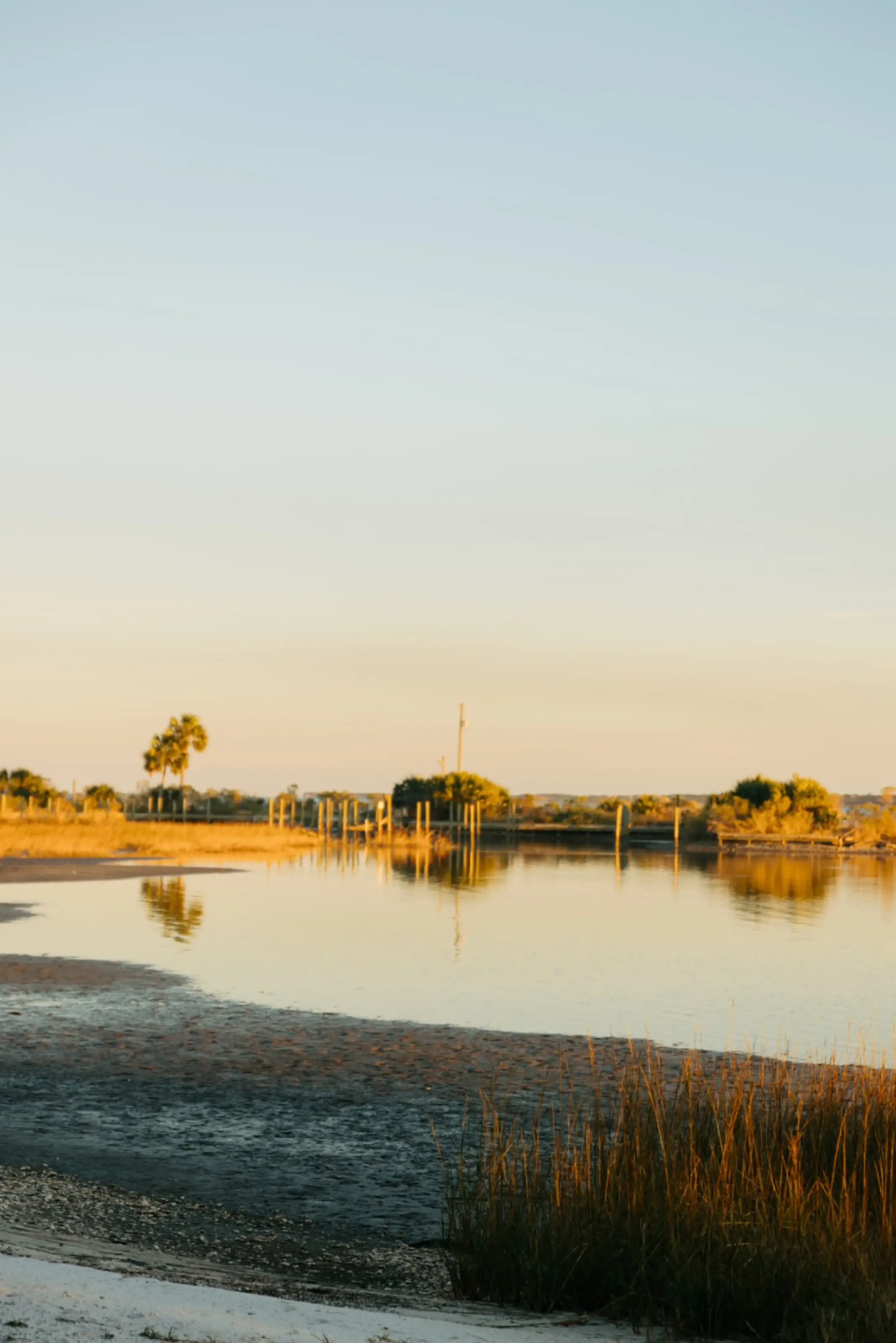 The tidal inlet below the house at sunset, marsh grass in silhouette against the water.