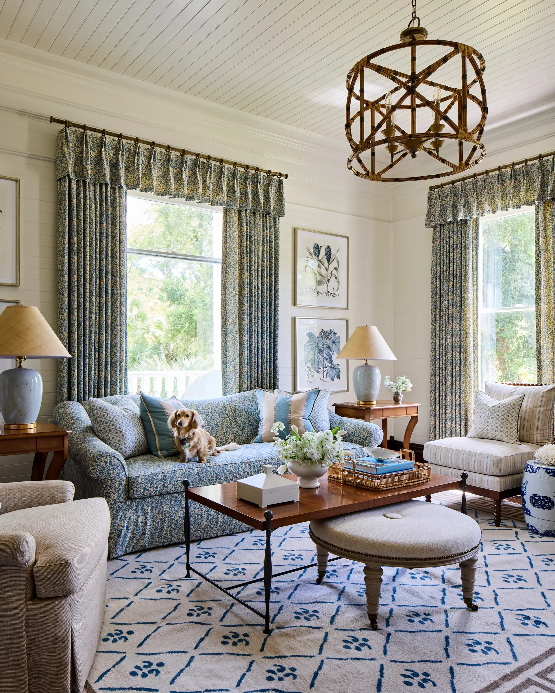 A sitting room in blue and white: two tall curtained windows, a slipcovered sofa and a bamboo lantern above the coffee table.